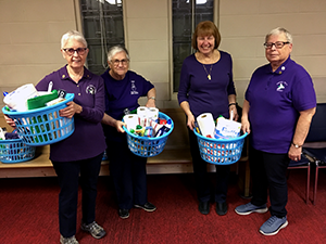 Trefoil Guild members with laundry baskets of household supplies for donation