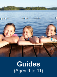 Five Girl Guides aged 9 to 11 posing on a dock at the side of a lake during a camping trip