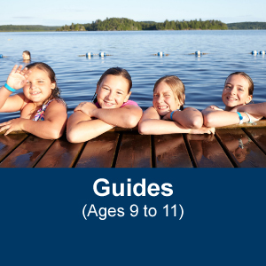 Five Girl Guides aged 9 to 11 posing on a dock at the side of a lake during a camping trip