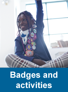 One girl wearing uniform and a sash full of badges raising her hand