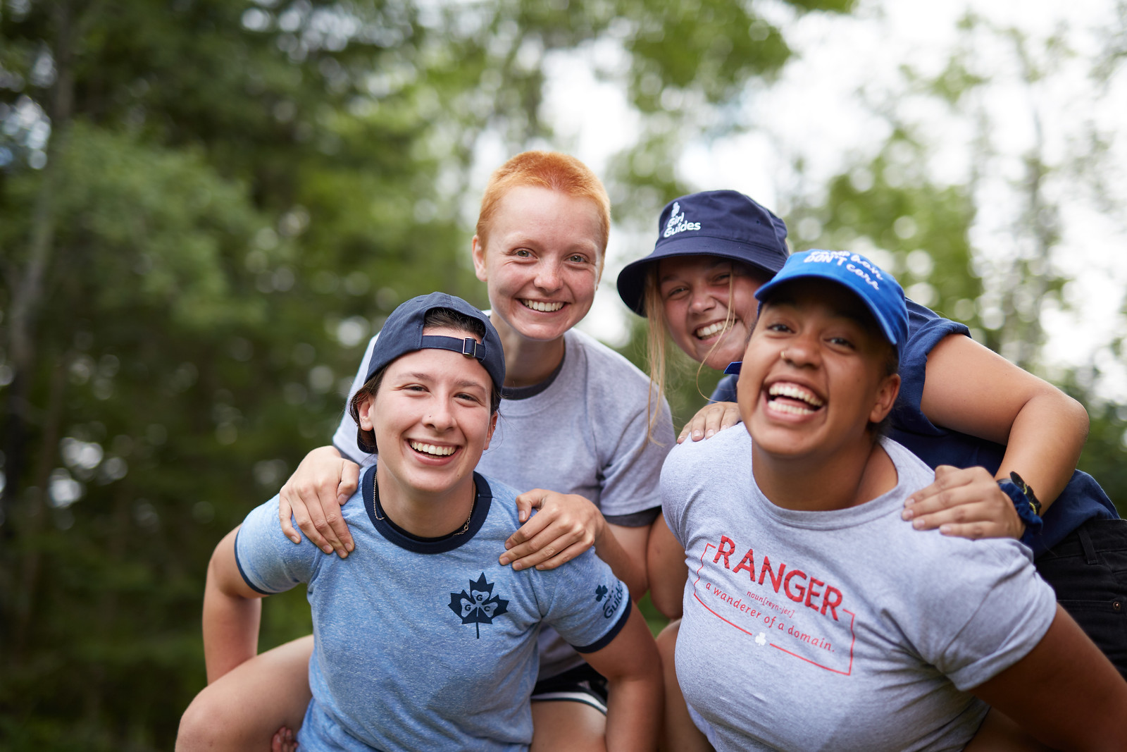 Four Girl Guides aged 15 to 17 posing together outside with two girls in front carrying the other two girls on their backs. 